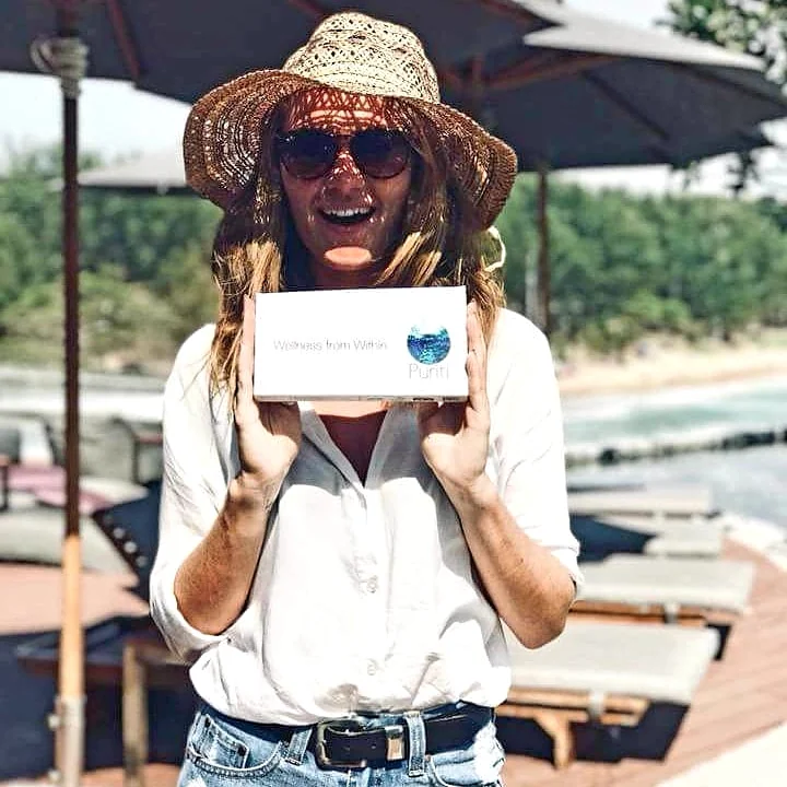 Trinity Napier holding a Puriti Box on a beach deck